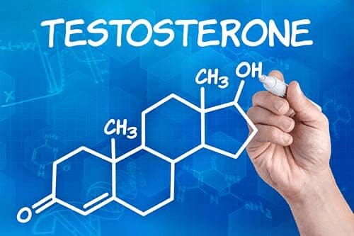 A hand writing testosterone on a blue background